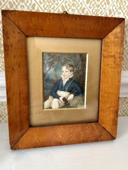 A DELIGHTFUL WATERCOLOUR IN A MAPLE FRAME OF A YOUNG BOY HOLDING A BOOK CIRCA 1860